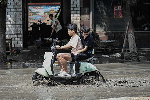 Hôm 09/08/2023, người dân địa phương đi xe máy qua những con đường lầy lội sau trận lũ ở thành phố Trác Châu, tỉnh Hà Bắc, Trung Quốc. Phần lớn địa khu cũng như vùng ngoại ô thành phố và các khu vực lân cận bị ngập lụt, cơ sở hạ tầng bị hư hại nghiêm trọng. (Ảnh: Jade Gao/AFP)