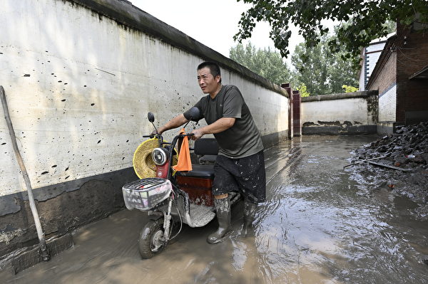 Hôm 09/08/2023, một người dân địa phương đi bộ trên con đường lầy lội sau trận lũ ở thành phố Trác Châu, tỉnh Hà Bắc, Trung Quốc. (Ảnh: Jade Gao/AFP)