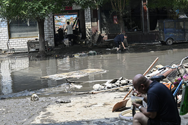 Hôm 09/08/2023, một người dân (trái) đang dọn dẹp đống đổ nát sau trận mưa lớn ở thành phố Trác Châu, tỉnh Hà Bắc, Trung Quốc. (Ảnh: Jade Gao/AFP)