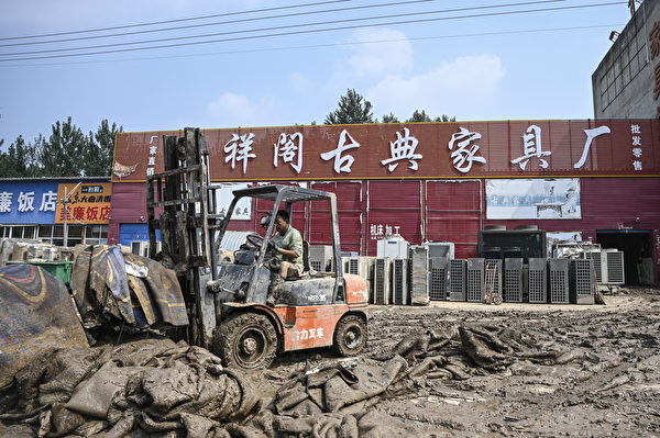 Hôm 09/08/2023, công nhân dọn dẹp bùn đất bên ngoài một cửa hàng nội thất sau lũ lụt ở thành phố Trác Châu, tỉnh Hà Bắc, Trung Quốc. (Ảnh: Jade Gao/AFP)