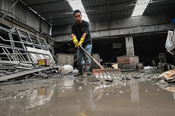 Hôm 09/08/2023, công nhân dọn dẹp bùn đất và mảnh vụn tại một nhà kho bị hư hại sau trận lũ lụt ở thành phố Trác Châu, tỉnh Hà Bắc, Trung Quốc,. (Ảnh: Jade Gao/AFP)