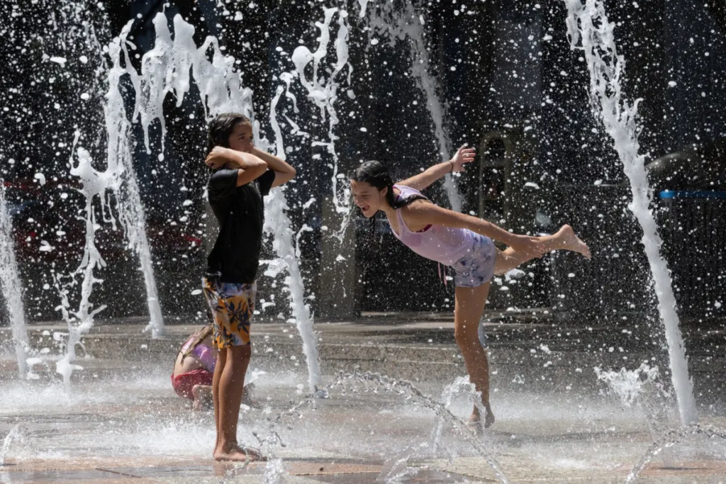 Hai chị em Olivia, 10 tuổi và Evelyn Black, 12 tuổi, chơi ở Gateway Fountains tại công viên Discovery Green để tránh thời tiết nóng bức ở Houston, Texas, hôm 18/07/2023. (Ảnh: Adrees Latif/Reuters)