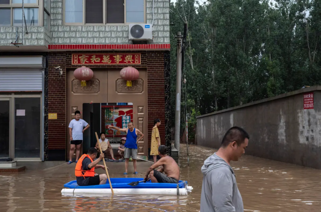 Một số người dân ngồi trên một chiếc thuyền tạm bợ, nói chuyện trước nhà của họ ở khu vực ngập trong nước lũ gần Trác Châu, tỉnh Hà Bắc, phía nam Bắc Kinh, Trung Quốc, hôm 03/08/2023. (Ảnh: Kevin Frayer/Getty Images)