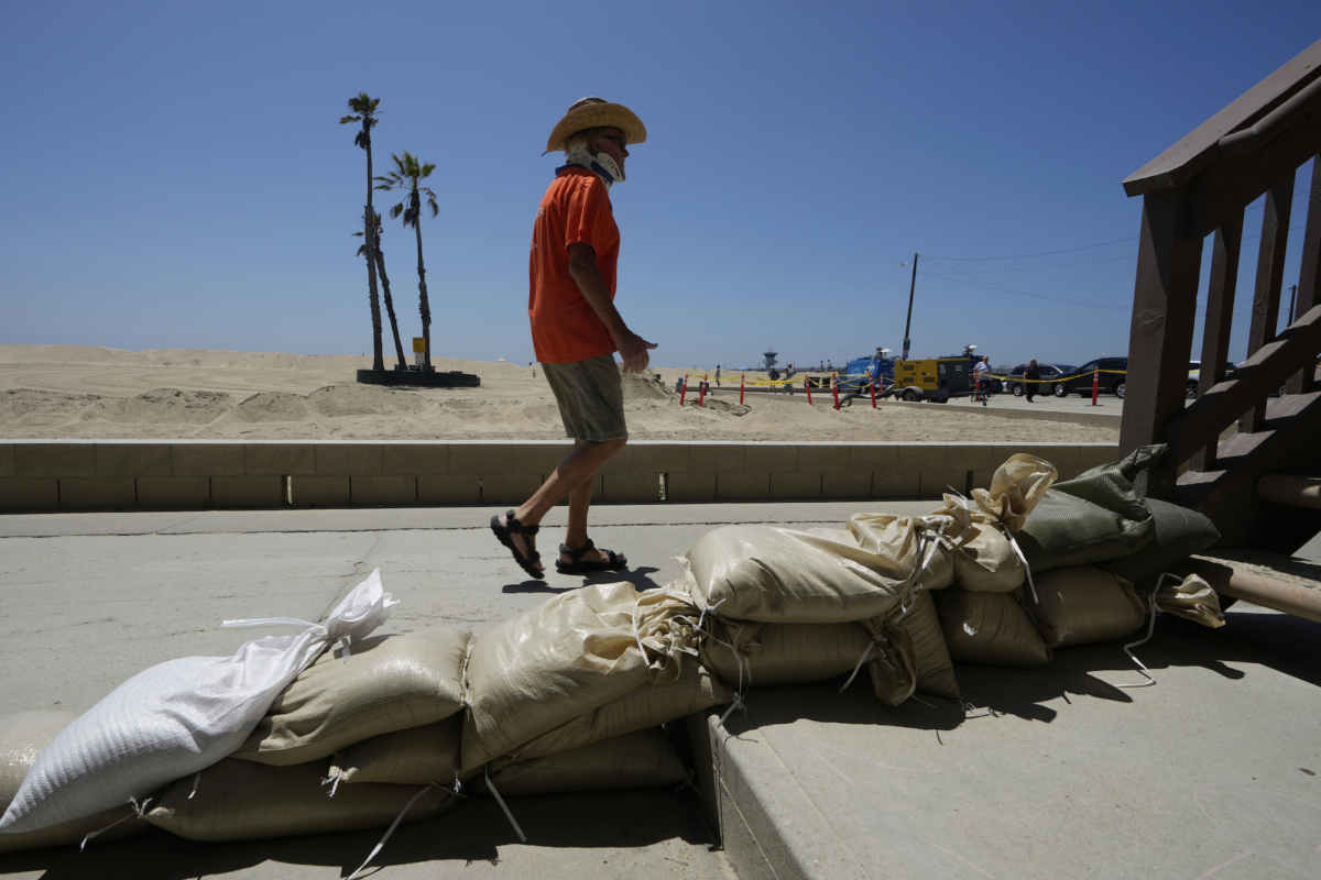 Một cư dân Seal Beach đi ngang qua một ngôi nhà được bảo vệ bằng bao cát ở Seal Beach, California, hôm 24/08/2023. (Ảnh: Damian Dovarganes/AP Photo)