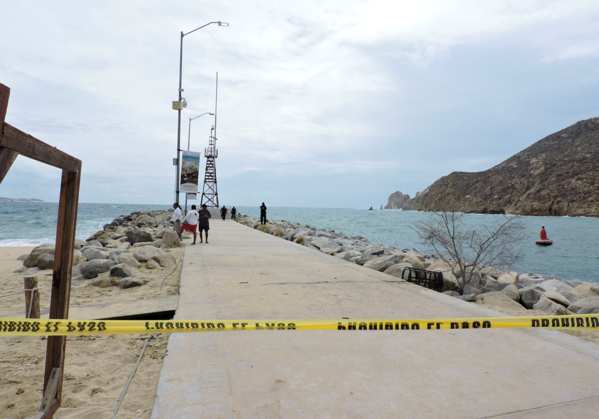 Các sĩ quan cảnh sát và nhân viên cứu hộ đứng tại đê chắn sóng đã được chính quyền địa phương đóng cửa như một biện pháp an ninh, trong khi cơn bão Hilary đổ bộ vào bán đảo Baja California của Mexico, ở Cabo San Lucas, Mexico, hôm 18/08/2023. (Ảnh: Monserrat Zavala/Reuters)