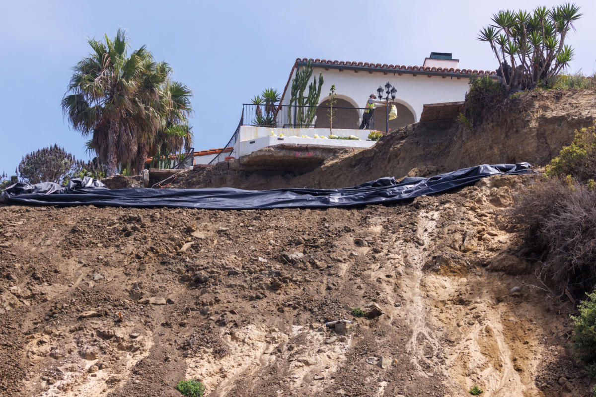 Các công nhân chuẩn bị che phủ một sườn đồi bị trượt bằng một tấm bạt nhựa với hy vọng bảo vệ nơi này khỏi cơn mưa dự kiến do cơn bão Hilary sắp tới ở San Clemente, California, hôm 18/08/2023. (Ảnh: Mike Blake/Reuters)