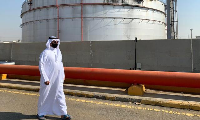 Một người đàn ông đeo khẩu trang do đại dịch virus corona COVID-19 đi ngang qua một bình chứa bị hư tại cơ sở dầu mỏ của Saudi Aramco ở thành phố Jeddah bên Hồng Hải của Saudi Arabia, hôm 24/11/2020. (Ảnh: Fayez Nureldine/AFP qua Getty Images)