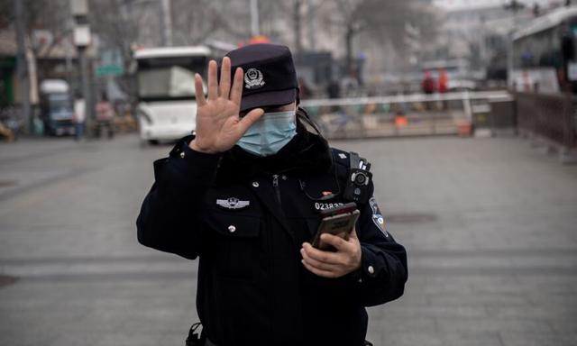 Một viên công an ra hiệu cho một ký giả không được chụp ảnh ở Bắc Kinh, vào ngày 05/03/2021. (Ảnh: Nicolas Asfouri/AFP qua Getty Images)