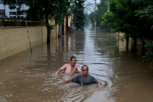 Người dân địa phương tìm cách vượt qua dòng nước sâu chảy xiết khi họ cố gắng đến được chỗ lực lượng cứu hộ ở trên một chiếc thuyền trong khu vực bị ngập trong nước lũ gần Trác Châu, tỉnh Hà Bắc, phía nam Bắc Kinh, hôm 03/08/2023. (Ảnh: Kevin Frayer/Getty Images)