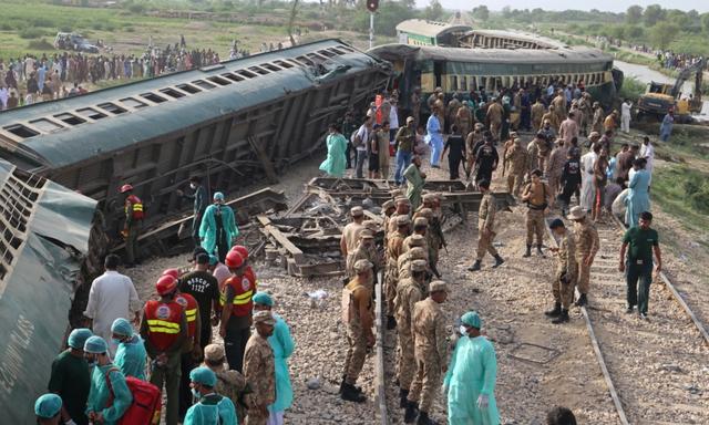 Lực lượng kiểm lâm bán quân sự và các tình nguyện viên kiểm tra các toa xe lửa tại địa điểm xảy ra tai nạn sau vụ trật đường ray của một đoàn xe lửa chở khách ở Nawabshah, Pakistan, hôm 06/08/2023. (Ảnh: Husnain Ali/AFP qua Getty Images)