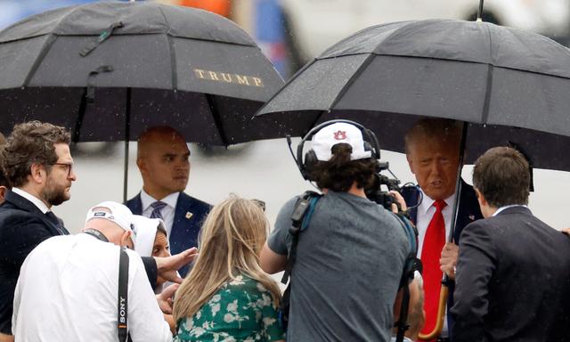 Ông Walt Nauta (bên trái) quan sát cựu Tổng thống Hoa Kỳ Donald Trump (bên phải) nói chuyện với các thành viên của giới truyền thông trên đường băng tại Phi trường Quốc gia Reagan ở Arlington, Virginia, sau một phiên tòa buộc tội tại một tòa án ở Thủ đô Hoa Thịnh Đốn, hôm 03/08/2023. (Ảnh: Tasos Katopodis/Getty Images)