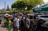 Người dân xếp hàng chờ nhận bữa ăn miễn phí tại một trung tâm phân phát cho những người bị đám cháy Maui ảnh hưởng tại Công viên Bãi biển Honokawai ở Napili-Honokowai, Tây Maui, Hawaii hôm 14/08/2023. (Ảnh: Yuki Iwamura/AFP qua Getty Images)