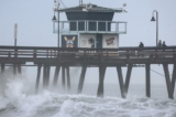 Người dân đứng trên một bến tàu nhìn ra Thái Bình Dương khi cơn bão nhiệt đới Hilary tiến đến quận San Diego ở Imperial Beach, California, hôm 20/08/2023. (Ảnh: Mario Tama/Getty Images)