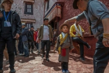 Một tín đồ Phật Giáo Tây Tạng đang chỉnh lại nón cho một cậu bé trong trang phục truyền thống khi đến thăm Cung điện Potala, một Di sản Thế giới được UNESCO công nhận, trong chuyến thăm do chính quyền tổ chức ở Lhasa, Tây Tạng, Trung Quốc, hôm 16/06/2023. (Ảnh: Kevin Frayer/Getty Images)