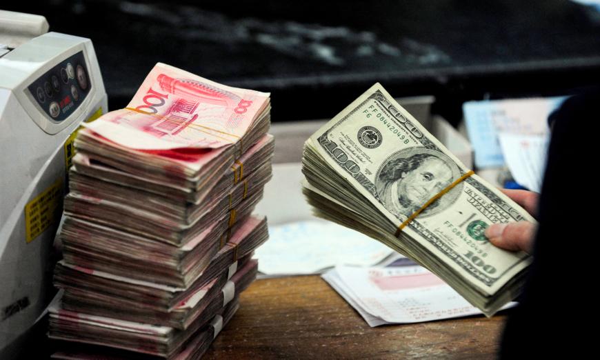 Một nhân viên ngân hàng Trung Quốc chuẩn bị đếm một chồng USD và các xấp tiền giấy 100 nhân dân tệ tại một ngân hàng ở Hợp Phì, tỉnh An Huy, Trung Quốc, hôm 09/03/2010. (Ảnh: STR/AFP qua Getty Images)