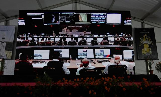 Các nhà khoa học của Tổ chức Nghiên cứu Vũ trụ Ấn Độ (ISRO) được chiếu trên màn hình đang chờ phi thuyền Chandrayaan-3 hạ cánh xuống mặt trăng tại cơ sở Mạng lưới Chỉ huy, Theo dõi và Đo từ xa của ISRO ở Bengaluru, Ấn Độ, hôm 23/08/2023. (Ảnh: Aijaz Rahi/ AP Photo)