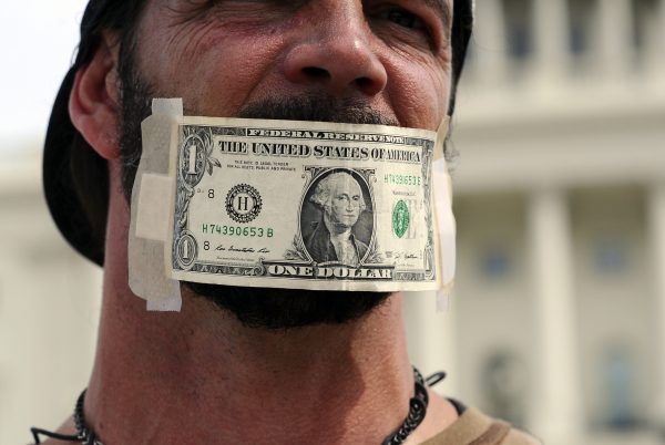 Một người biểu tình dán tờ 1 USD vào khẩu trang bịt miệng trong cuộc biểu tình trước Tòa nhà Quốc hội Hoa Kỳ ở Hoa Thịnh Đốn, hôm 03/10, để kêu gọi Quốc hội chấm dứt việc đóng cửa chính phủ liên bang. (Ảnh: Jewel Saad/AFP/Getty Images)