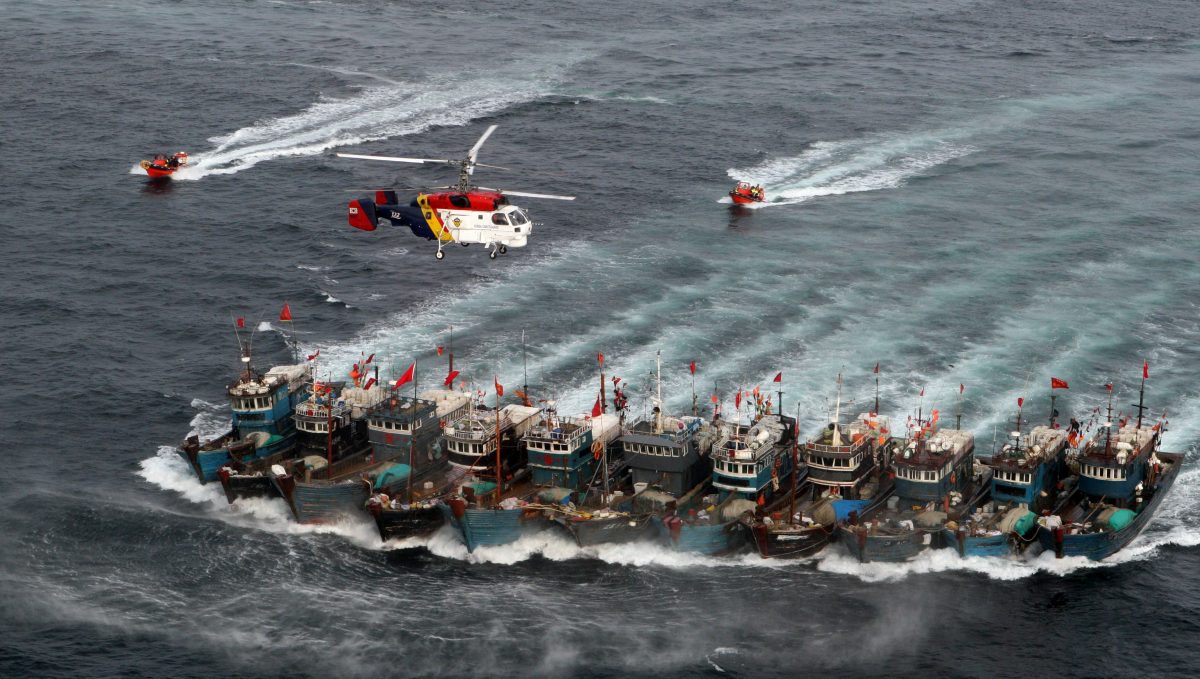 Khi đối đầu với các trực thăng và tàu của Lực lượng Tuần Duyên Nam Hàn ở Hoàng Hải vào tháng 11/2011, đoàn tàu đánh cá Trung Quốc này đã liên kết với nhau bằng dây thừng và lao ra biển khơi — đằng sau một lá chắn gồm các chiến hạm Trung Quốc. (Ảnh: Dong-a Ilbo/AFP/Getty Images)