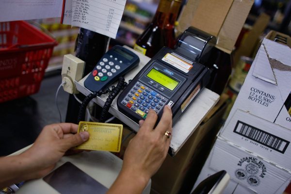 Bà Yera Dominguez sử dụng đầu đọc thẻ tín dụng để giải quyết khoản khoản thanh toán của khách hàng tại cửa hàng bách hóa Lorenzo's Italian Market ở Miami hôm 20/05/2009. (Ảnh: Joe Raedle/Getty Images)