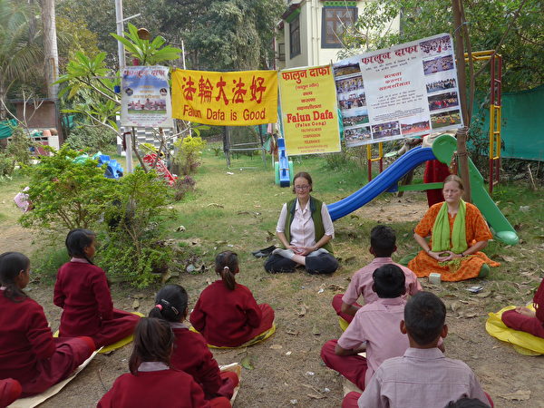 Cô Cornelia (trái) và cô Chris (phải) đang hướng dẫn cho trẻ em ở Sarnath, Ấn Độ bài công pháp thứ năm của Pháp Luân Đại Pháp, ảnh chụp vào mùa đông năm 2020. (Ảnh do cô Cornelia cung cấp)