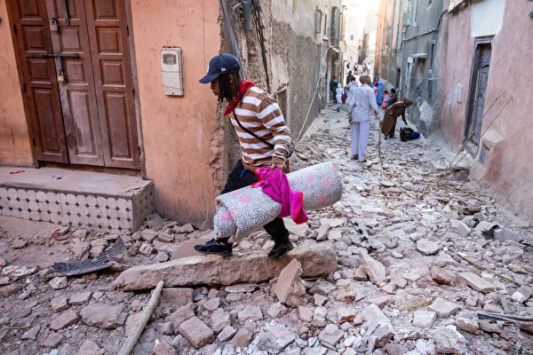 Hôm 09/09, tại Marrakech, Morocco, một người dân mang theo hành lý đi qua đống đổ nát. Tối ngày 08/09, một trận động đất mạnh 6.8 độ ở Morocco khiến hơn 2,000 người thiệt mạng. (Ảnh: Fadel Senna/AFP qua Getty Images)