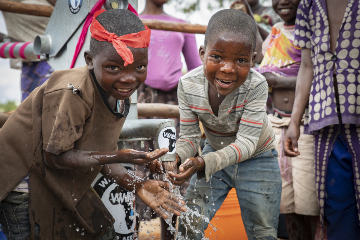 Trẻ em vui vẻ thưởng thức nước giếng sạch do tổ chức Water Wells for Africa xây dựng ở Làng Lupapa, Malawi, vào ngày 06/07/2021. (Ảnh: John Fredricks/The Epoch Times)
