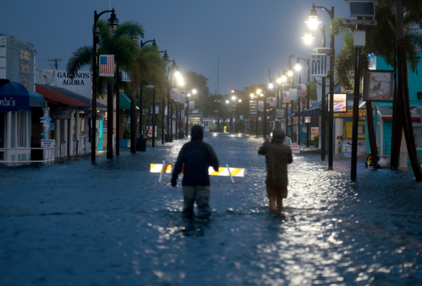 Các phóng viên lội qua vùng nước lũ tràn ngập đại lộ Dodecanese ở Tarpon Springs, Florida, vào sáng sớm ngày 30/08/2023 khi bão Idalia đi qua ngoài khơi. (Ảnh: Joe Raedle/Getty Images)