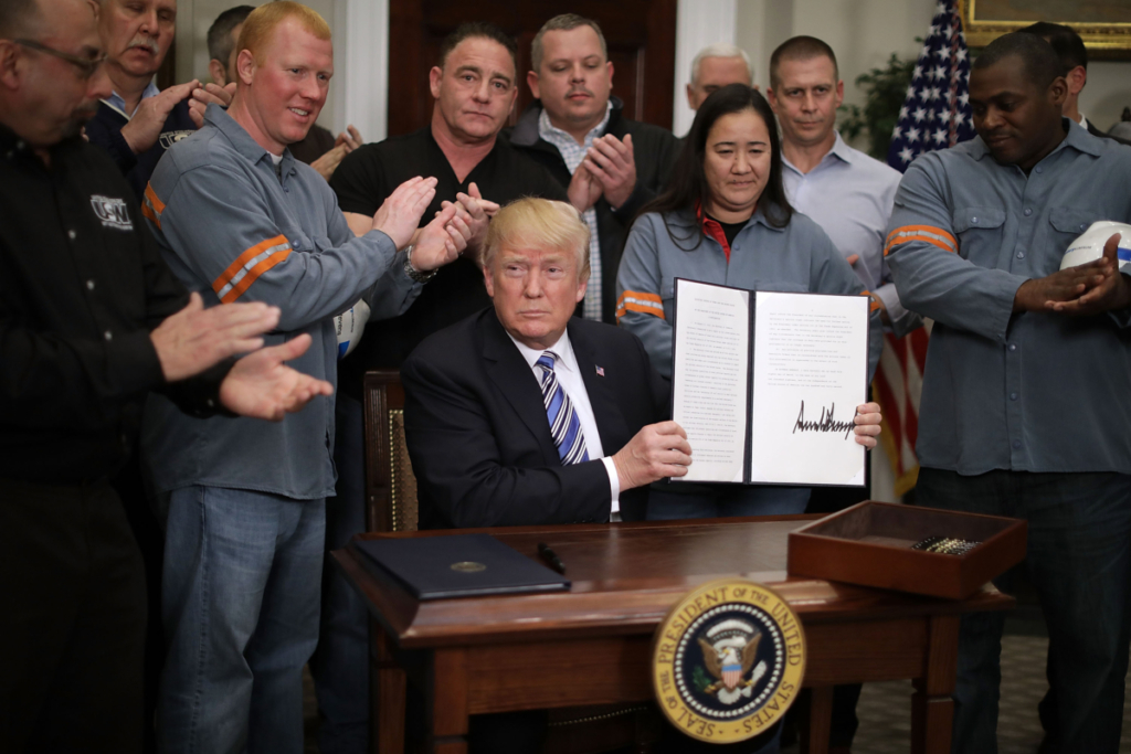 Các nhân viên ngành thép và nhôm vỗ tay khi cựu Tổng thống Hoa Kỳ Donald Trump giơ cao “Tuyên bố Mục 232” về nhập cảng thép, được ký tại Phòng Roosevelt của Tòa Bạch Ốc, hôm 08/03/2018. (Ảnh: Chip Somodevilla/Getty Images)