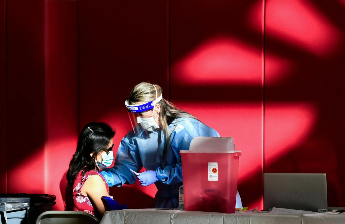 Một người phụ nữ nhận được một mũi vaccine COVID-19 tại nhà thi đấu của Trường Trung học Corona ở Corona, California, vào ngày 15/01/2021. (Ảnh: Frederic J. Brown/AFP qua Getty Images)
