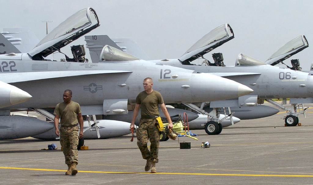 Các nhân viên phi cơ của lực lượng thủy quân lục chiến Hoa Kỳ đi ngang qua những chiếc F-18 của Phi đội tấn công chiến đấu cơ 122 của thủy quân lục chiến Hoa Kỳ sau khi họ hạ cánh xuống Căn cứ Không quân Clark, một căn cứ cũ của Hoa Kỳ, từ Iwakuni, Nhật Bản, để tham gia cuộc tập trận huấn luyện quân sự chung kéo dài hai tuần với các đối tác Philippines được gọi là Talon Vision 2007, vào ngày 12/10/2006. (Ảnh: Jay Directo/AFP qua Getty Images)
