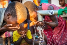 Trẻ em thưởng thức từng ngụm nước sạch tại một vòi nước giếng do tổ chức Water Wells for Africa (Giếng Nước Cho Châu Phi) xây dựng ở Làng Maggie B, Malawi, vào ngày 30/06/2021. (Ảnh: John Fredricks/The Epoch Times)