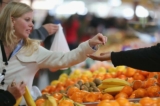 Một người phụ nữ trả tiền cho người bán trái cây tại một khu chợ ở Melbourne, Úc, vào ngày 23/07/2013. (Ảnh: Scott Barbour/Getty Images)