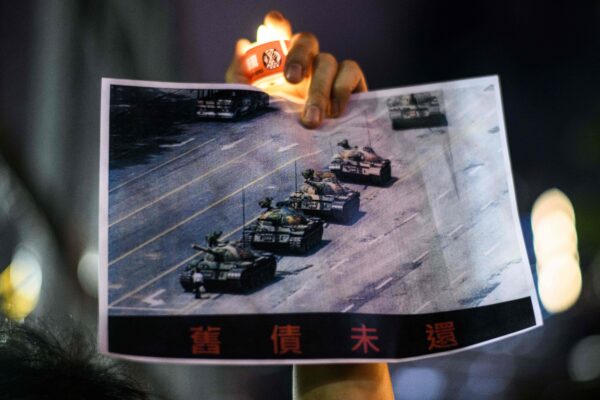 Một người đàn ông cầm tấm bích chương có hình ‘Người chặn xe tăng’ nổi tiếng trong Vụ thảm sát Thiên An Môn năm 1989, trong buổi tưởng niệm dưới ánh nến ở Công viên Victoria ở Hồng Kông vào ngày 04/06/2020. (Ảnh: Anthony Wallace/AFP qua Getty Images)