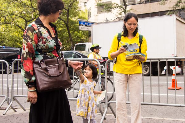 Một bé gái và mẹ phát tờ rơi về môn tu luyện Pháp Luân Công ở New York vào ngày 20/09/2016. (Ảnh: Larry Dai/Epoch Times)