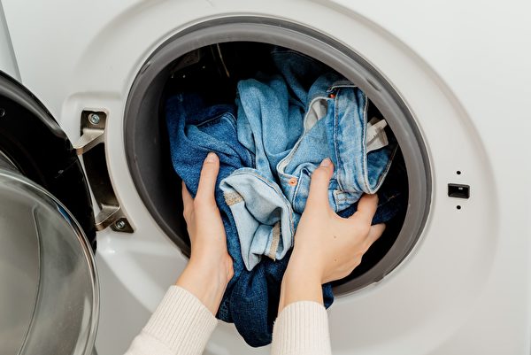 Hình ảnh một người phụ nữ giặt quần jean bằng máy giặt. (Ảnh: Shutterstock)