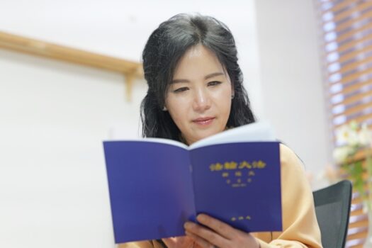 Cô Seon Ah Son, chủ tịch của Công ty Siêu sao Siêu sao Quốc tế, đang đọc một cuốn sách Pháp Luân Đại Pháp (Ảnh: Jaehyun Park/The Epoch Times)