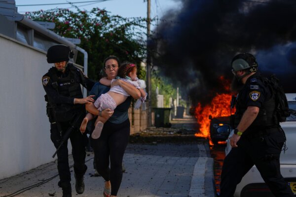 Các cảnh sát sơ tán một phụ nữ và một đứa trẻ khỏi địa điểm bị trúng hỏa tiễn từ Dải Gaza, ở Ashkelon, miền nam Israel, hôm 07/10/2023. (Ảnh: Tsafrir Abayov/AP Photo)