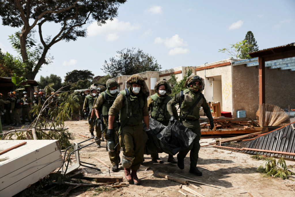 Binh sĩ Israel đang khiêng thi thể một nạn nhân trong vụ tấn công khủng bố từ Gaza tại Kibbutz Kfar Aza, miền nam Israel, hôm 10/10/2023. (Ảnh: Violeta Santos Moura/Reuters)