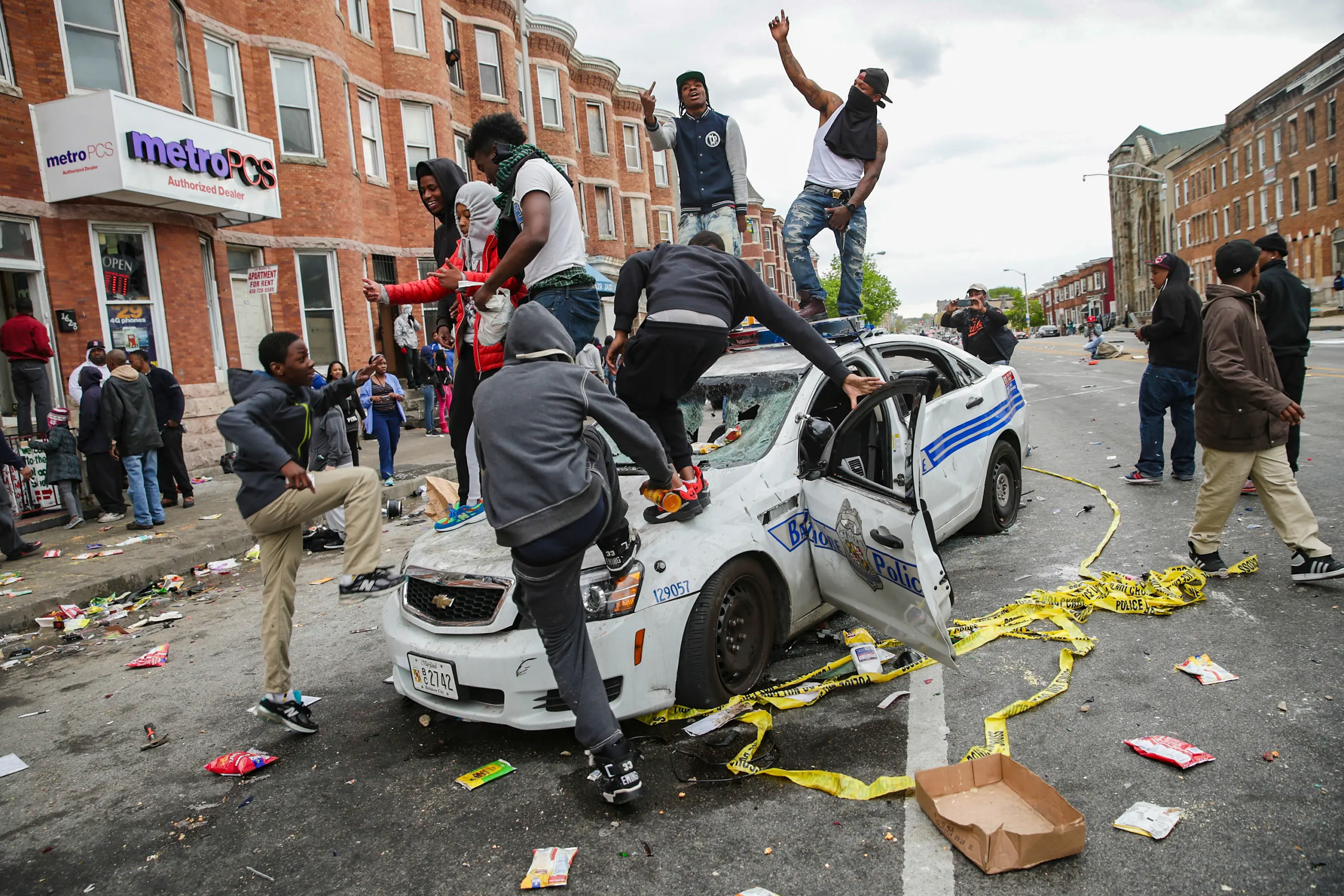 Người biểu tình leo lên một chiếc xe cảnh sát Baltimore bị phá hủy trên đường phố trong cuộc biểu tình bạo lực sau đó ở Baltimore vào ngày 27/04/2015