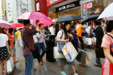 Trong bức ảnh ngày 17/06/2015 này, khách du lịch Trung Quốc cầm túi mua sắm đang chờ xe buýt tham quan trước một cửa hàng điện tử giảm giá ở quận Ginza của Tokyo. (Ảnh: AP Photo/Shizuo Kambayashi)