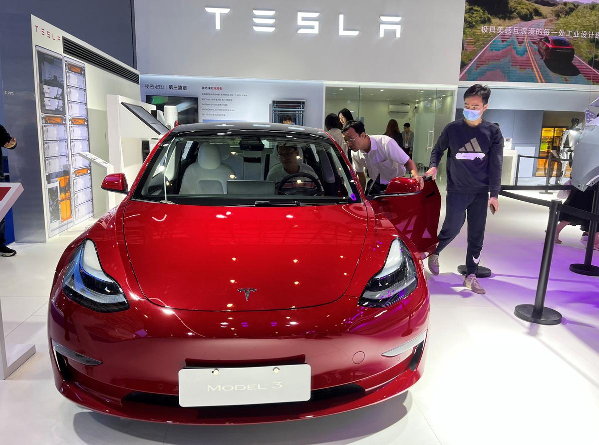 Khách tham quan ngắm nhìn chiếc xe điện Tesla Model 3 tại Triển lãm Sản phẩm Tiêu dùng Quốc tế Trung Quốc lần thứ ba ở Hải Khẩu, tỉnh Hải Nam, Trung Quốc, hôm 12/04/2023. (Ảnh: Casey Hall/Reuters)