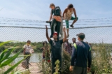 Những người nhập cư bất hợp pháp giúp nhau trèo qua hàng rào thép gai từ Mexico vào Hoa Kỳ, ở Eagle Pass, Texas, hôm 15/08/2023. (Ảnh: Suzanne Cordeiro/AFP qua Getty Images)
