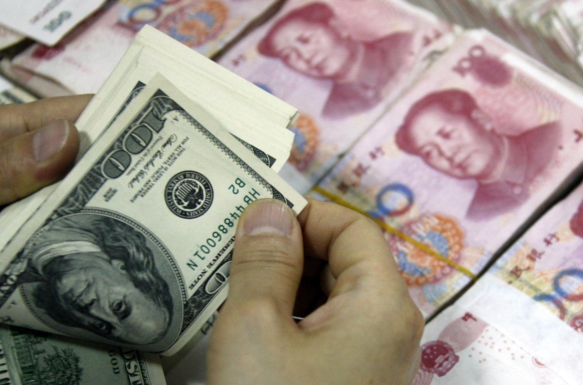 Các tờ bạc USD được đếm bên cạnh các tờ tiền 100 nhân dân tệ (RMB) tại một ngân hàng ở Hoài Bắc, tỉnh An Huy, miền đông Trung Quốc, hôm 24/09/2013. (Ảnh: STR/AFP qua Getty Images)