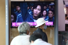 Người dân xem màn hình TV chiếu hình ảnh nam diễn viên Nam Hàn Lee Jung-jae trong phim “Squid Game” (Trò Chơi Con Mực) trong chương trình tin tức tại ga xe lửa Seoul ở Seoul, Nam Hàn, vào ngày 13/09/2022. (Ảnh: Chung Sung-Jun/Getty Images)