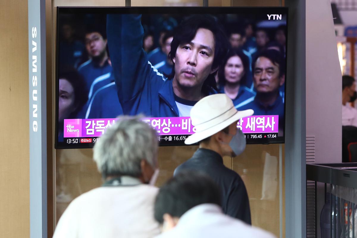 Người dân xem màn hình TV chiếu hình ảnh nam diễn viên Nam Hàn Lee Jung-jae trong phim “Squid Game” (Trò Chơi Con Mực) trong chương trình tin tức tại ga xe lửa Seoul ở Seoul, Nam Hàn, vào ngày 13/09/2022. (Ảnh: Chung Sung-Jun/Getty Images)