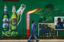 Một công nhân đi ngang qua bảng quảng cáo có hình bia và Ngọn đuốc Olympic tại Nhà máy bia Thanh Đảo, nhà máy bia lớn nhất Trung Quốc và là Nhà tài trợ bia nội địa chính thức cho Thế vận hội Olympic Bắc Kinh 2008 tại Thanh Đảo, tỉnh Sơn Đông, Trung Quốc, vào 25/04/2008. (Ảnh: Trung Quốc/Getty Images)