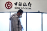Một người đàn ông đi ngang qua một quầy giao dịch của Ngân hàng Trung Quốc (Bank of China) tại Trung tâm Báo chí Chính của Thế vận hội Mùa Đông 2022 ở Bắc Kinh hôm 28/01/2022. (Ảnh: Fabrice Coffrini/AFP qua Getty Images)