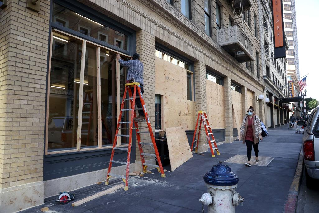 Một công nhân đang lắp các tấm ván ép bên ngoài một cơ sở kinh doanh đã đóng cửa ở San Francisco, California, vào ngày 16/04/2021. (Ảnh: Justin Sullivan/Getty Images)