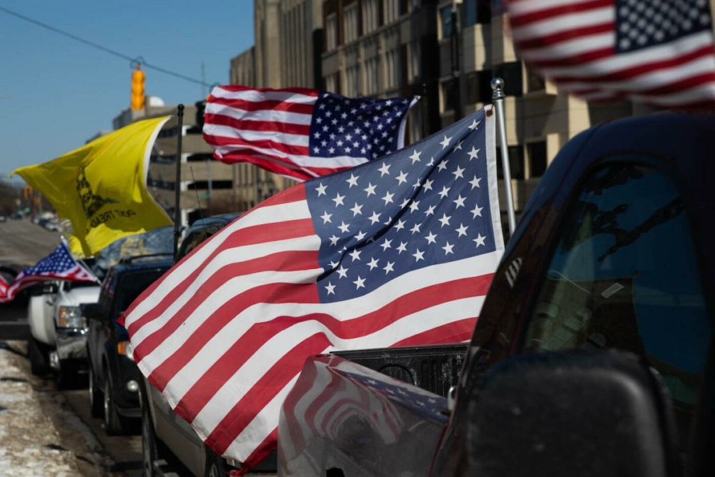 Quốc kỳ Mỹ tung bay trong gió khi những chiếc xe hơi xếp hàng tham gia Đoàn xe Tự do (Freedom Convoy) ở Lansing, Michigan, vào ngày 20/02/2022. (Ảnh: Emily Elconin/Getty Images)