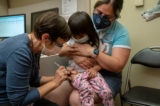 Một đứa trẻ 2 tuổi được y tá chích liều vaccine Pfizer COVID-19 đầu tiên trong lúc được mẹ bế, tại Trung tâm Y tế UW-Roosevelt ở Seattle, tiểu bang Washington, hôm 21/06/2022. (Ảnh: David Ryder/Getty Images)
